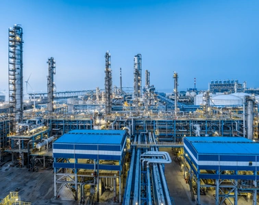 Нефтегазоперерабатывающий объект с ректификационными колоннами и трубопроводами под голубым небом