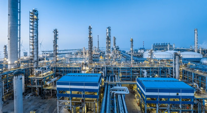 Нефтегазоперерабатывающий объект с ректификационными колоннами и трубопроводами под голубым небом
