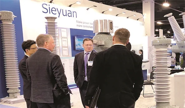 Посетители беседуют с сотрудниками Sieyuan на стенде компании на выставке IEEE PES T&D